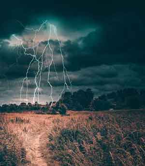 A path leading to a lightning storm over a field.